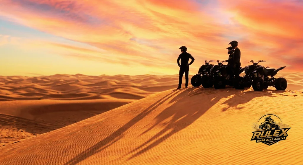 Quad bikes parked on a high Dubai desert dune during sunset with orange sky creating a beautiful and peaceful adventure photography scene