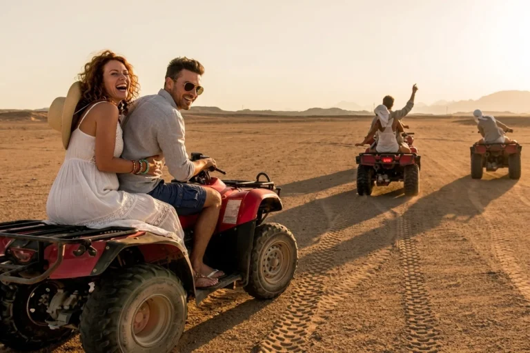What is Quad Biking in Dubai – rider enjoying a quad biking adventure across the red sand dunes of the Dubai desert