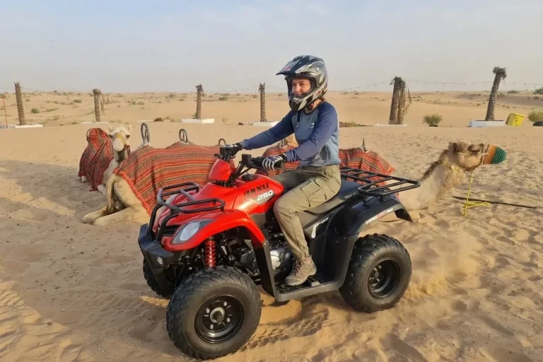 Quad Bike Rental Dubai experience showing quad bike speeding over tall sand dunes in Dubai desert with dust trail and wide landscape off road adventure UAE desert